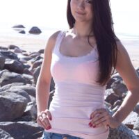 Small dark haired first timer displays her pointy teener boobs while outdoors on a rocky beach