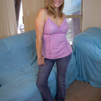Barefoot blonde strips to her bra and g-string on a couch