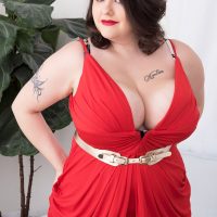 Tattooed BIG SEXY WOMAN Nagini takes off a red dress while making her naked debut on a chesterfield