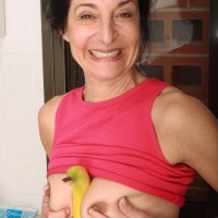 Mature lady strips naked in the kitchen before taking a banana to her unshaven beaver